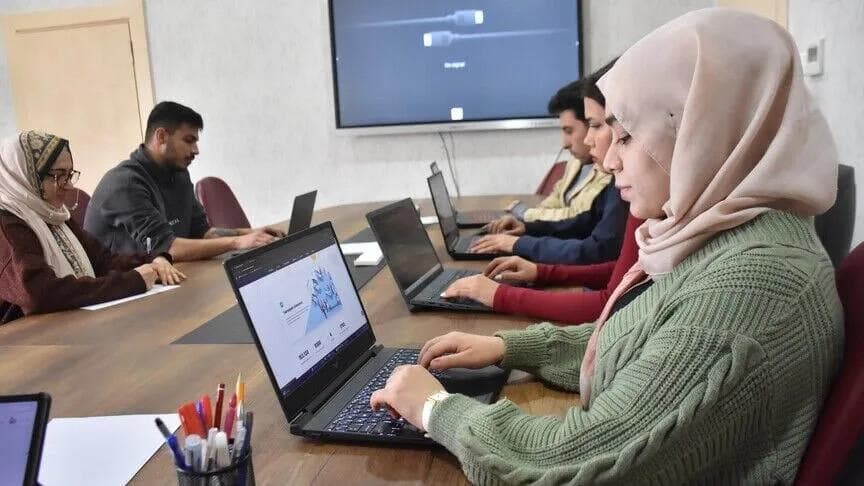 چند متخصص جوان پشت میز جلسه با لپتاپ کار میکنند